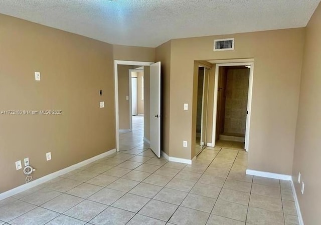 tiled empty room featuring a textured ceiling