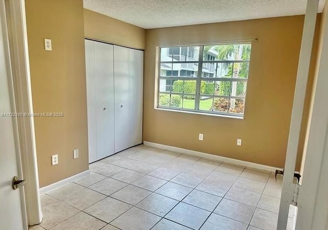 unfurnished bedroom with a closet, light tile patterned floors, and a textured ceiling