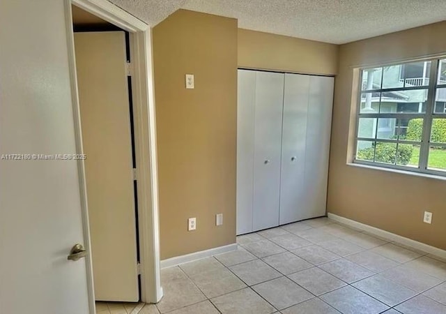 unfurnished bedroom featuring a closet, light tile patterned floors, and a textured ceiling