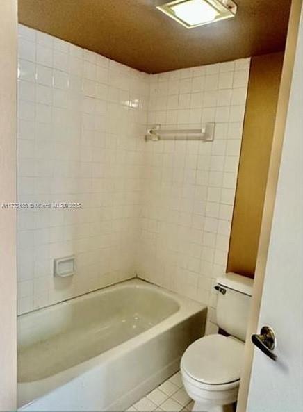 bathroom with shower / washtub combination, tile patterned flooring, and toilet