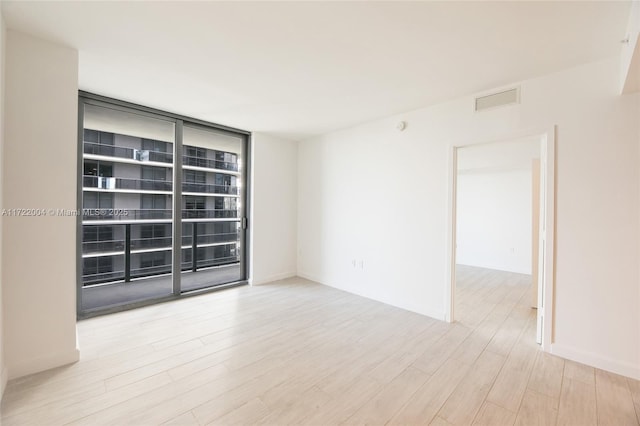 unfurnished room with light wood-type flooring and expansive windows