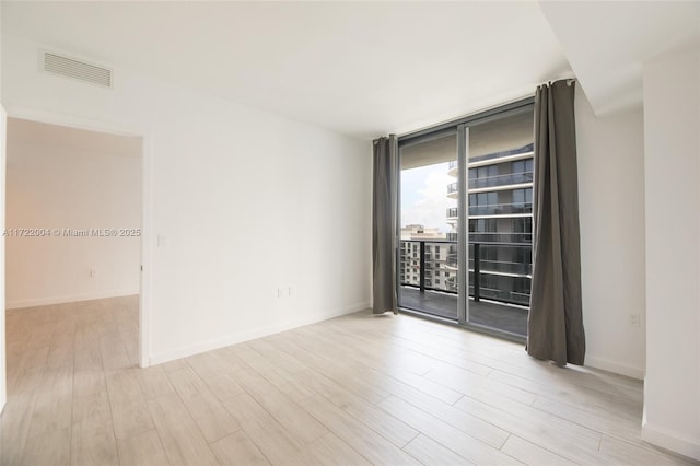 unfurnished room with light hardwood / wood-style floors and a wall of windows