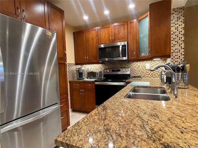 kitchen with light stone counters, sink, stainless steel appliances, and tasteful backsplash