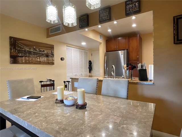 kitchen featuring stainless steel fridge and hanging light fixtures