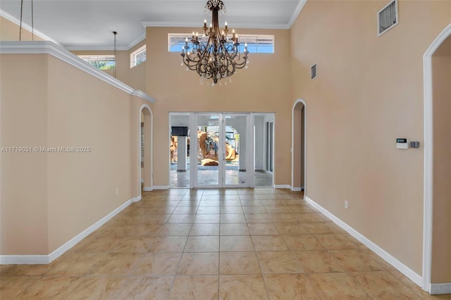 tiled foyer with a towering ceiling, an inviting chandelier, and crown molding