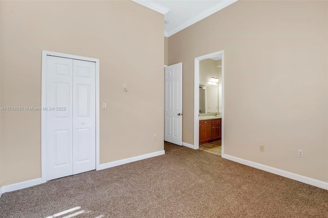 unfurnished bedroom featuring a closet, crown molding, connected bathroom, and light carpet