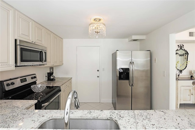 kitchen featuring sink, stainless steel appliances, light stone counters, a notable chandelier, and light tile patterned floors