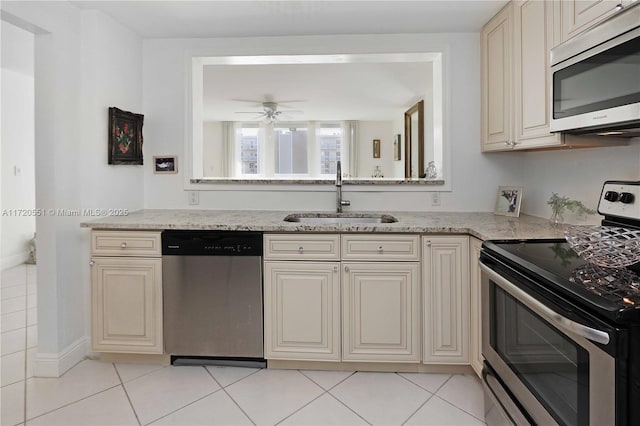 kitchen featuring light stone countertops, ceiling fan, sink, cream cabinetry, and appliances with stainless steel finishes