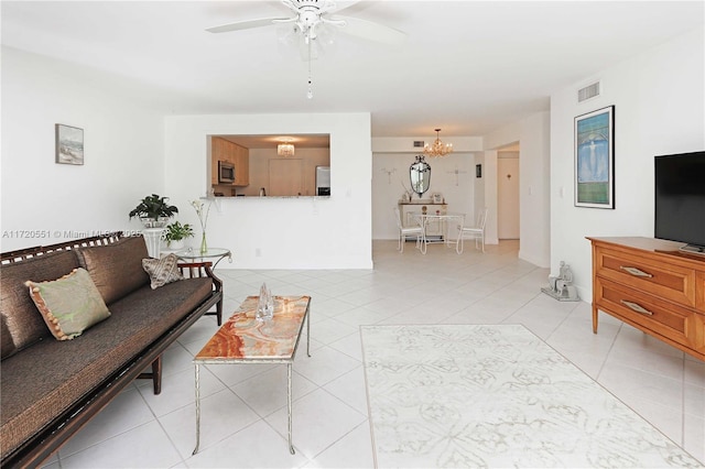 tiled living room with ceiling fan with notable chandelier