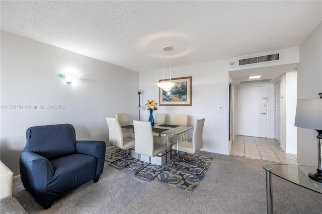 carpeted dining room featuring a textured ceiling