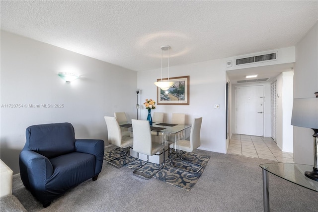 carpeted dining space with visible vents and a textured ceiling