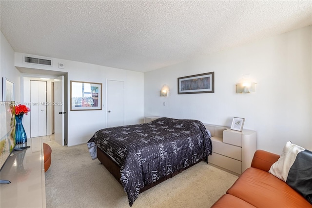 carpeted bedroom featuring a textured ceiling, visible vents, and a closet