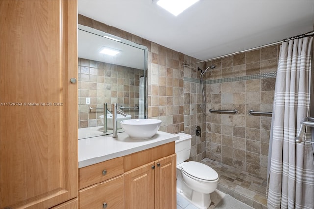 full bath featuring tile walls, vanity, tile patterned floors, toilet, and a tile shower