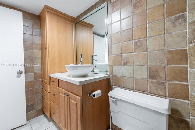 half bath featuring toilet, tile patterned floors, tile walls, and vanity