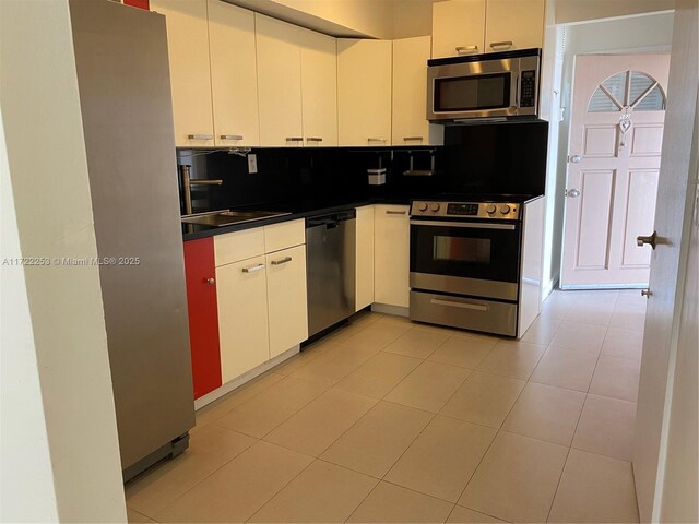 kitchen featuring white cabinets, light tile patterned flooring, and stainless steel appliances