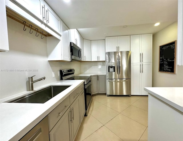 kitchen featuring light tile patterned floors, stainless steel appliances, white cabinetry, and sink