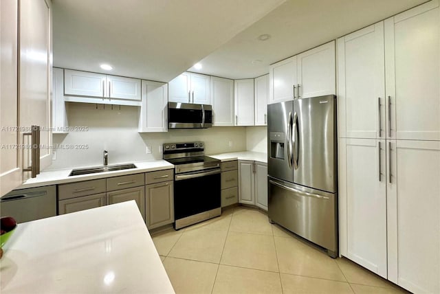 kitchen with gray cabinetry, white cabinets, sink, light tile patterned floors, and appliances with stainless steel finishes