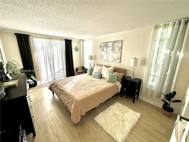 bedroom with light hardwood / wood-style floors, ornamental molding, and a textured ceiling