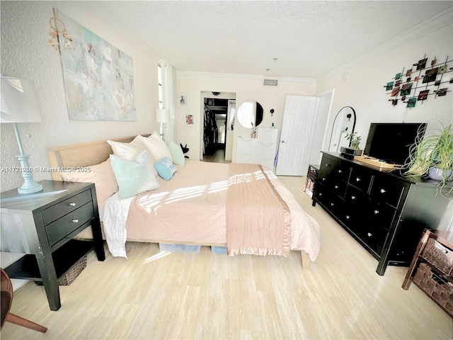 bedroom featuring crown molding, a textured ceiling, and light wood-type flooring