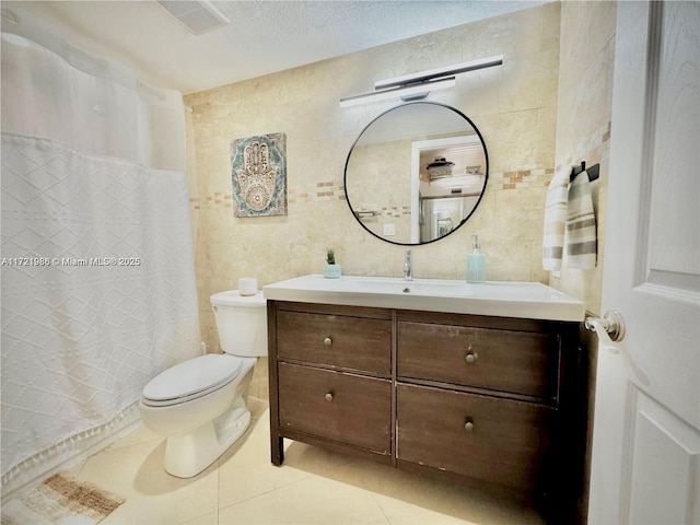 bathroom with tile patterned floors, a textured ceiling, vanity, tile walls, and toilet