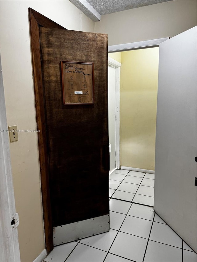 corridor with light tile patterned floors and a textured ceiling