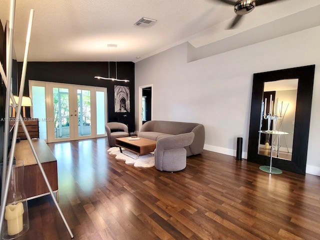 living room featuring a textured ceiling, dark wood-type flooring, lofted ceiling, and french doors