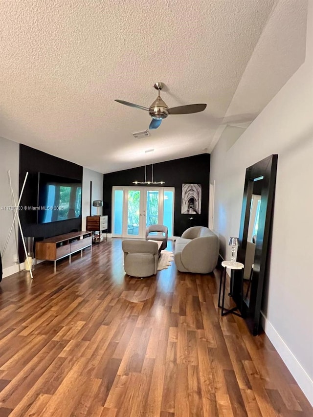 living room with ceiling fan, a textured ceiling, hardwood / wood-style flooring, and lofted ceiling