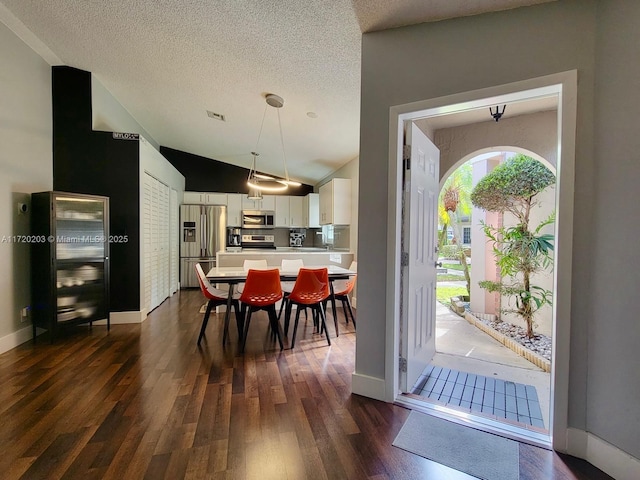 dining room with lofted ceiling, dark wood-type flooring, and a textured ceiling