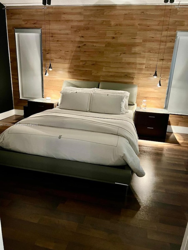 bedroom with hardwood / wood-style flooring and wooden walls