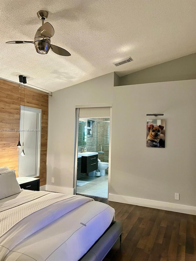 bedroom with a textured ceiling, connected bathroom, wood-type flooring, vaulted ceiling, and ceiling fan