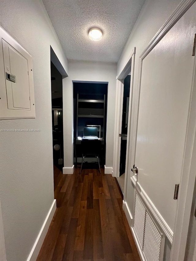 hall with a textured ceiling, electric panel, and dark hardwood / wood-style floors