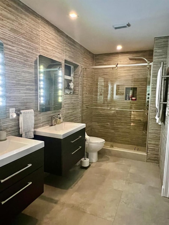 bathroom featuring an enclosed shower, vanity, tile walls, and toilet