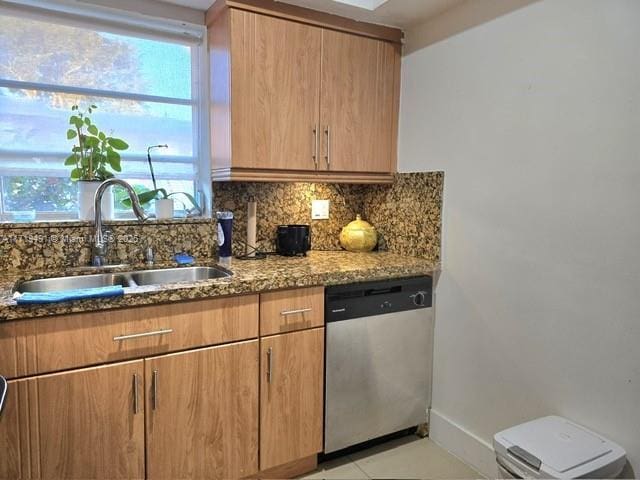 kitchen featuring stone countertops, baseboards, decorative backsplash, stainless steel dishwasher, and a sink