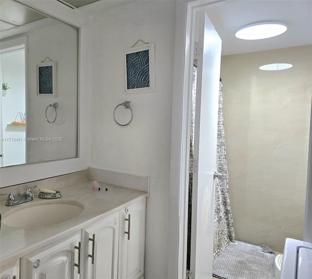 bathroom with a tile shower and vanity