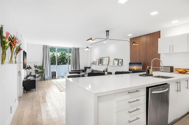 kitchen with floor to ceiling windows, white cabinetry, sink, and light wood-type flooring