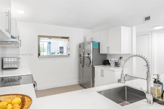 kitchen featuring stainless steel fridge, sink, white cabinets, and stove