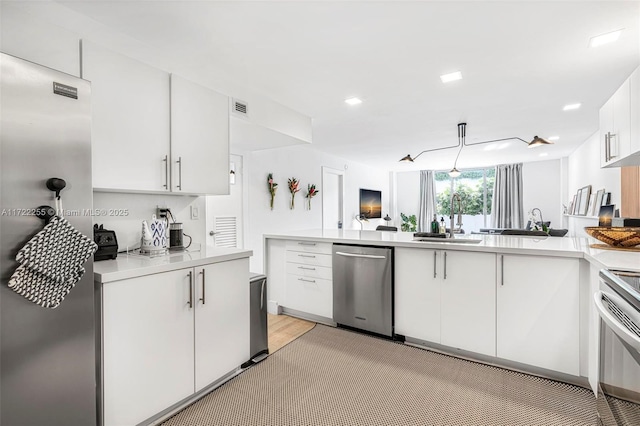 kitchen featuring kitchen peninsula, light wood-type flooring, stainless steel appliances, sink, and white cabinets