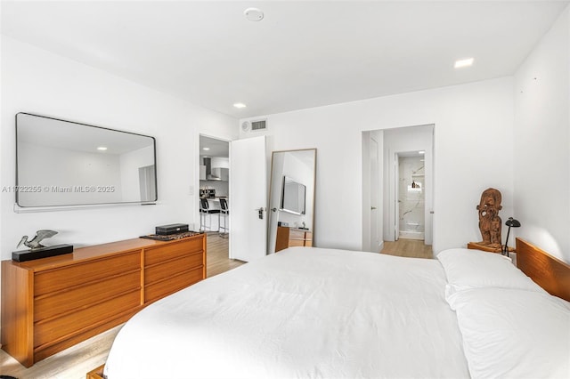 bedroom featuring light wood-type flooring and ensuite bathroom