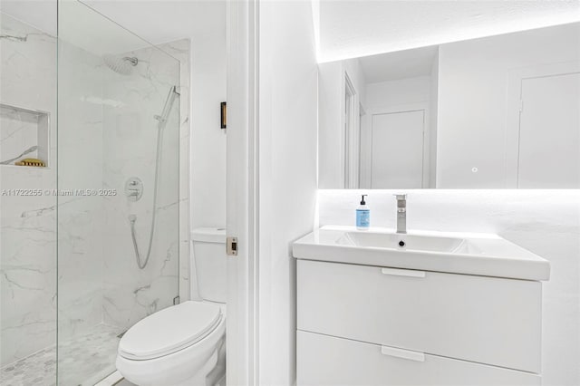 bathroom with a tile shower, vanity, and toilet