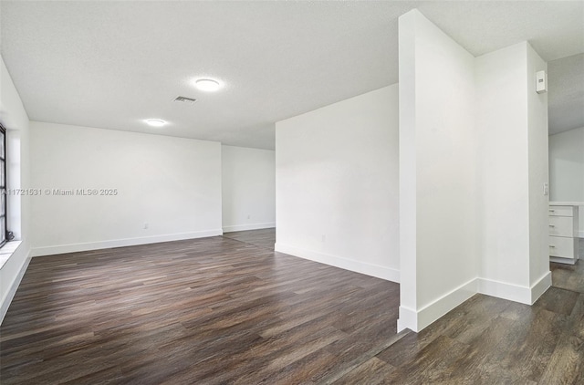 unfurnished room with a textured ceiling and dark hardwood / wood-style floors