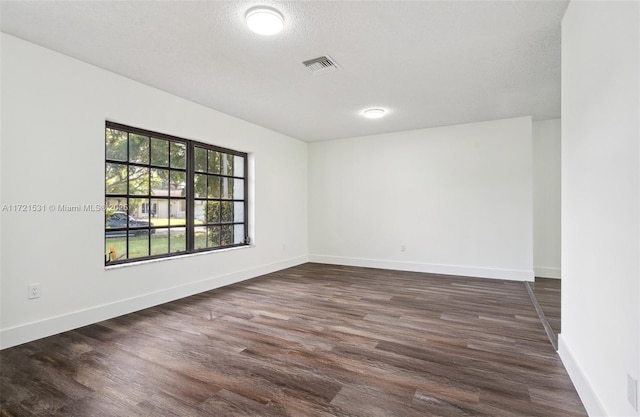 empty room with a textured ceiling and dark hardwood / wood-style floors