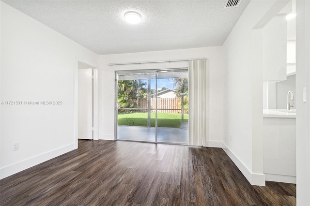 unfurnished room with sink, dark wood-type flooring, and a textured ceiling