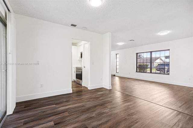 unfurnished living room with a textured ceiling and dark hardwood / wood-style flooring