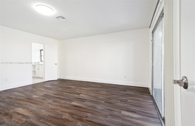 spare room featuring a textured ceiling and dark hardwood / wood-style flooring