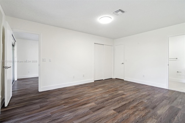 spare room featuring a textured ceiling and dark wood-type flooring