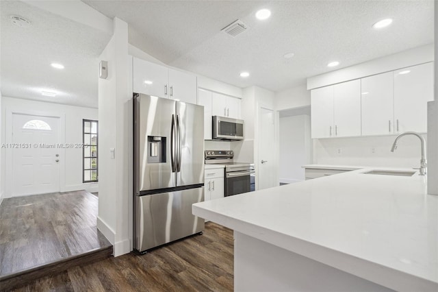 kitchen featuring white cabinetry, dark hardwood / wood-style flooring, a textured ceiling, and appliances with stainless steel finishes