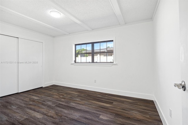 unfurnished bedroom featuring beam ceiling, a textured ceiling, a closet, and dark wood-type flooring