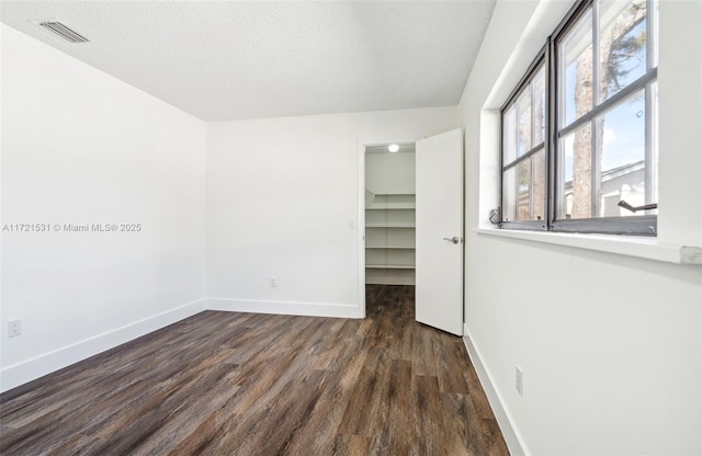 unfurnished room with a textured ceiling and dark hardwood / wood-style flooring