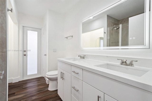 bathroom with hardwood / wood-style flooring, vanity, a shower with shower door, and toilet