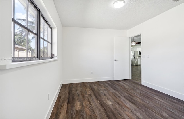 spare room featuring a textured ceiling, ceiling fan, and dark wood-type flooring